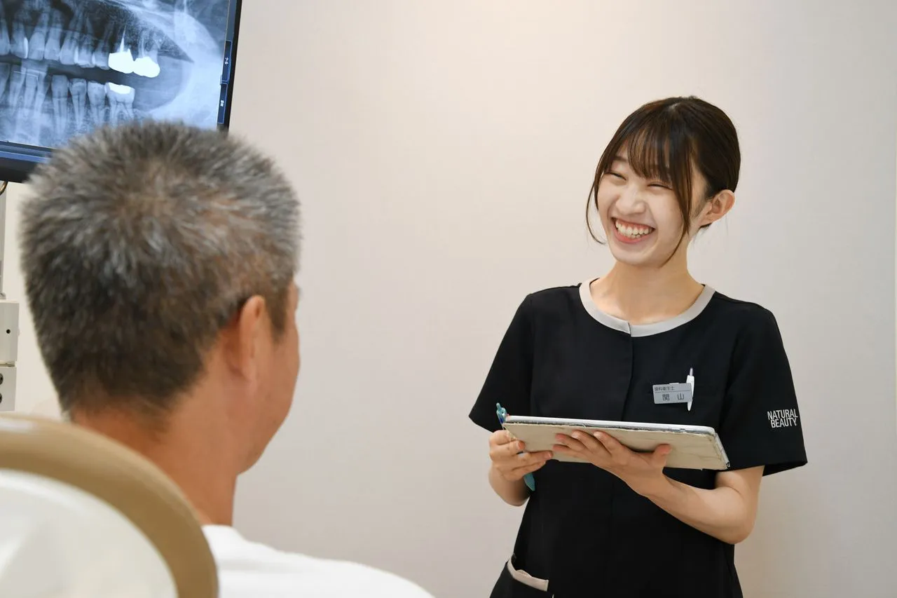 歯科医院で患者に治療内容を説明しているスタッフの様子