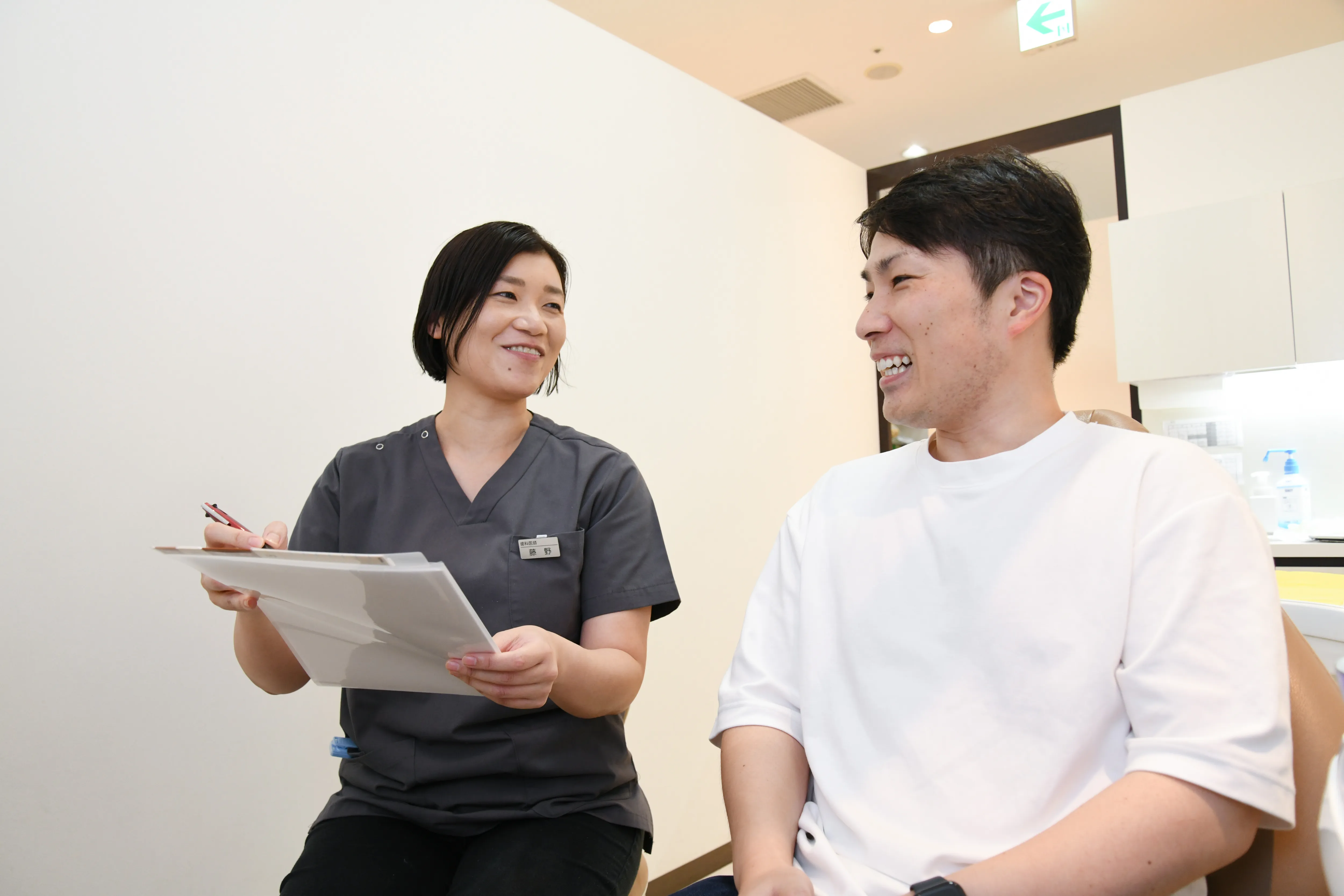 問診票を確認しながら、患者に治療内容を説明している。